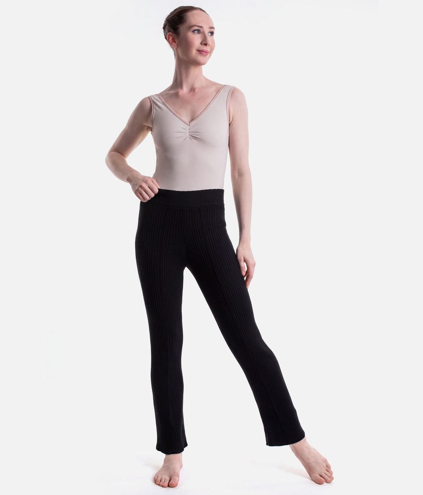 Full front view of Black Capezio Mise-En-Scene Nolan warm-up pants, showing the fitted hips and wider legs over a pale ballet leotard.