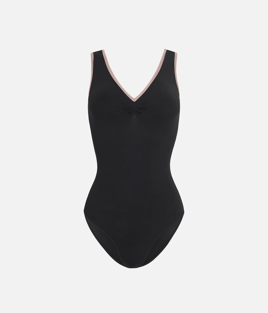 A black one-piece leotard with a V-neckline and a small gathered detail at the center chest, featuring light pink trim along the neckline, shown against a light gray background.