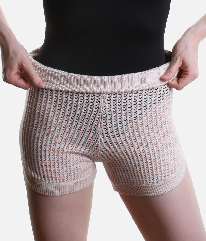Close-up of Pink Anderson shorts showing the ribbed side band, small side slit and pointelle knit with a black leotard visible beneath.