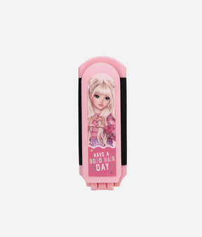 A pink folding hair clip with a cartoon doll illustration on the front and the text 'HAVE A GOOD HAIR DAY' printed below, shown against a plain light gray background.
