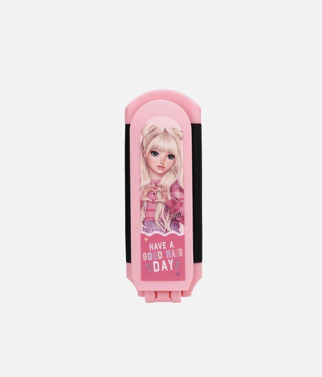 A pink folding hair clip with a cartoon doll illustration on the front and the text 'HAVE A GOOD HAIR DAY' printed below, shown against a plain light gray background.