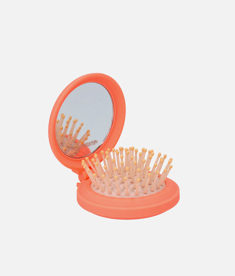 Open orange Miss Melody folding hairbrush showing the built-in mirror and pale bristles with golden-yellow rounded tips