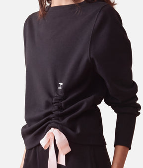 Close-up of Repetto S0797 black sweatshirt showing the round neckline, small r logo and gathered side with a pale-pink bow.