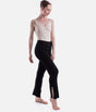 Black Capezio Nolan ribbed knit pants in a crossed-leg pose, showing the opening at the lower-leg hem and the full-length shape.