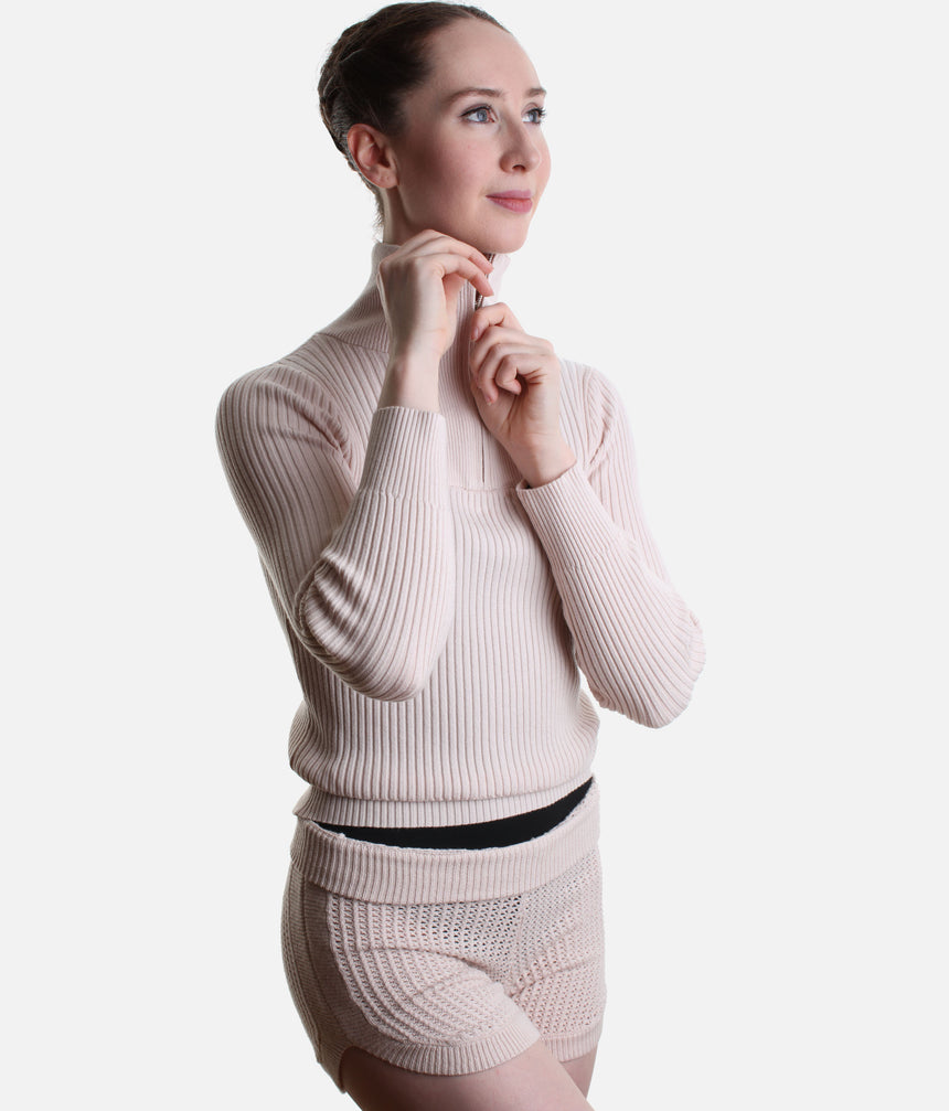 Pink Capezio Lynch knit jumper with the quarter zip raised, showing its high collar and ribbed cuffs, styled with Anderson shorts.
