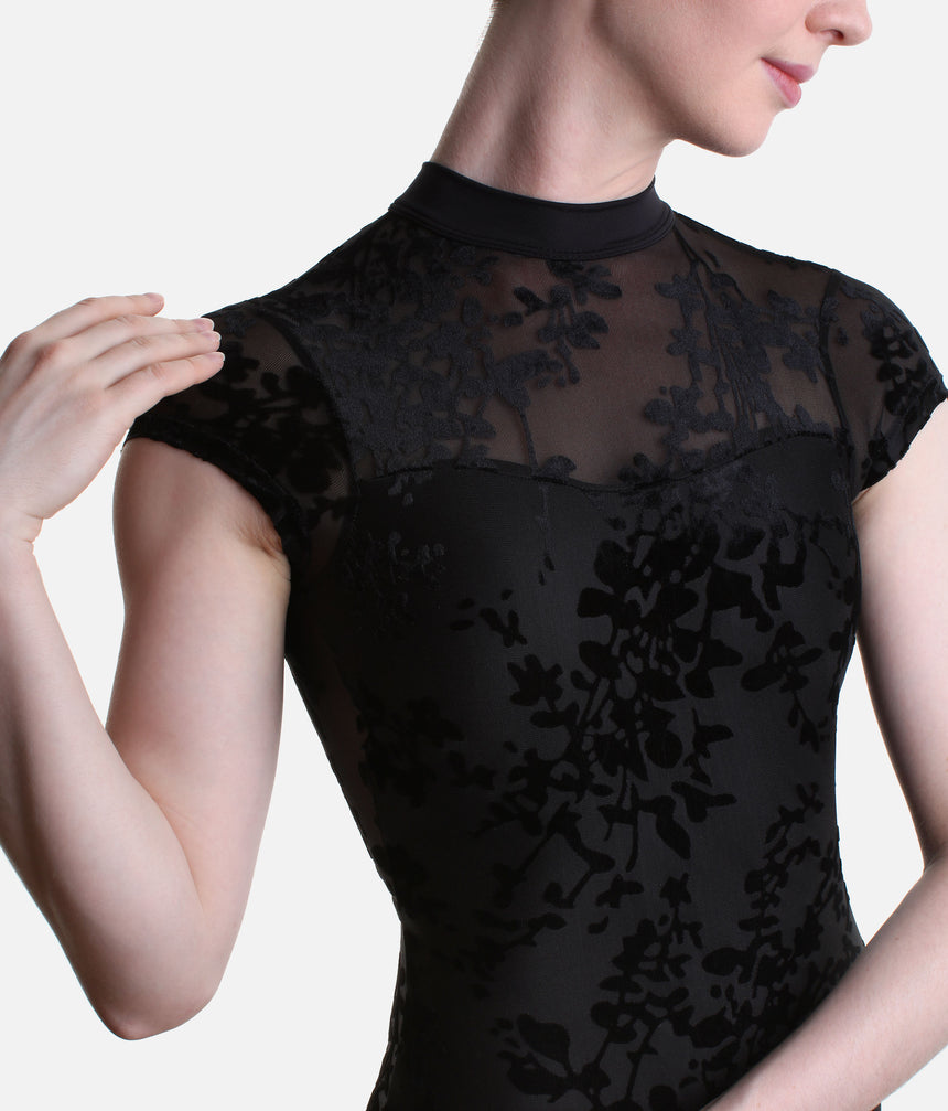 Close-up of the Black Rudi leotard’s mock neckline, sheer upper-chest yoke and floral burnout pattern across the short sleeves and bodice.