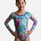 Mondor Hieroglyph 17895 girls’ long sleeve gymnastics leotard with a colourful graphic print, fine dark markings and blue-trimmed round neckline.