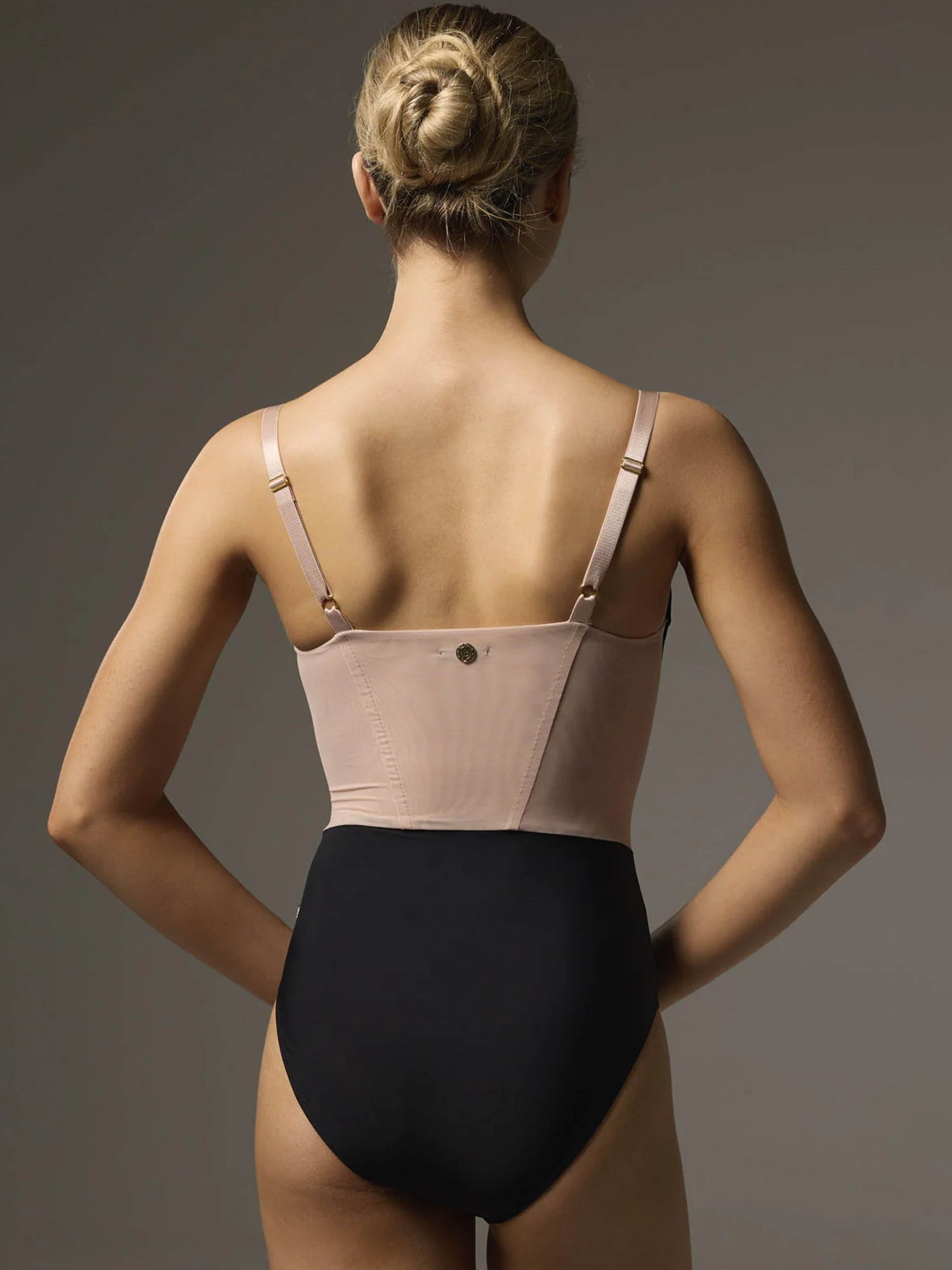 Back of Bodile Bella Noire Nougat leotard, showing the nougat mesh panel, adjustable straps, gold hardware and black lower body.