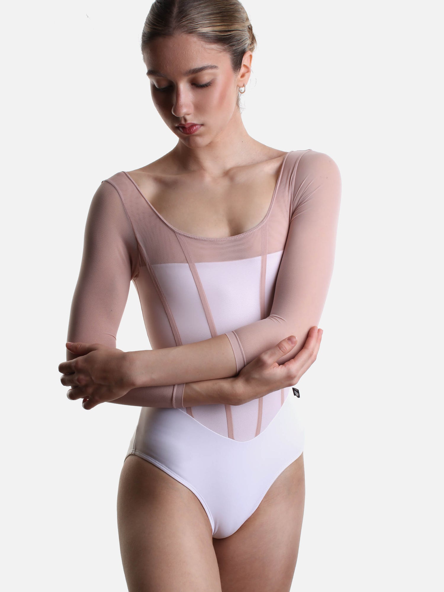 Model wearing Bodile Sofia Frost Nougat leotard with arms crossed, showing the pink mesh sleeves and panelled bodice.