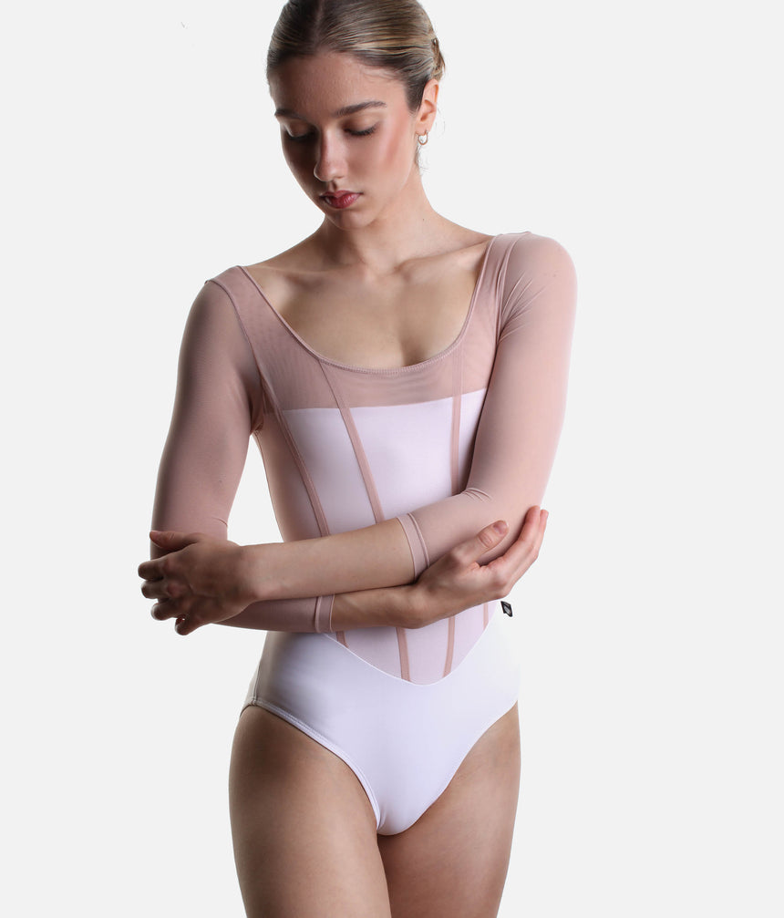 Model wearing Bodile Sofia Frost Nougat leotard with arms crossed, showing the pink mesh sleeves and panelled bodice.