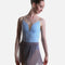 A female dancer wearing a light blue leotard with a deep V-neckline and a sheer gray tulle skirt, posed against a solid light gray background.