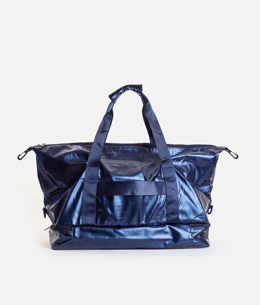 A shiny navy blue duffel bag with dual top handles and a front utility pocket, photographed against a clean off-white background.