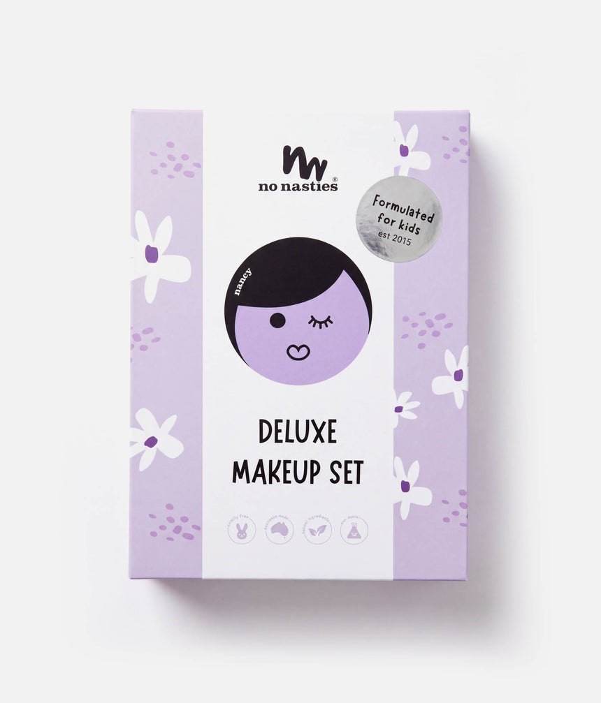 The packaging box for the 'no nasties Deluxe Makeup Set' is shown against a clean white background. The box features a light purple and white color scheme with a cartoon illustration of a face with black hair and a silver seal that reads 'Formulated for kids'.