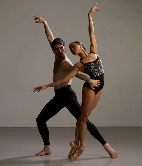 Dancer wearing Bodile Ophelia Leopard leotard in a supported ballet pose, showing the patterned bodice and black body.