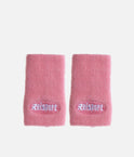 Pair of pink Reisport towelling wristbands laid flat with white embroidered logos