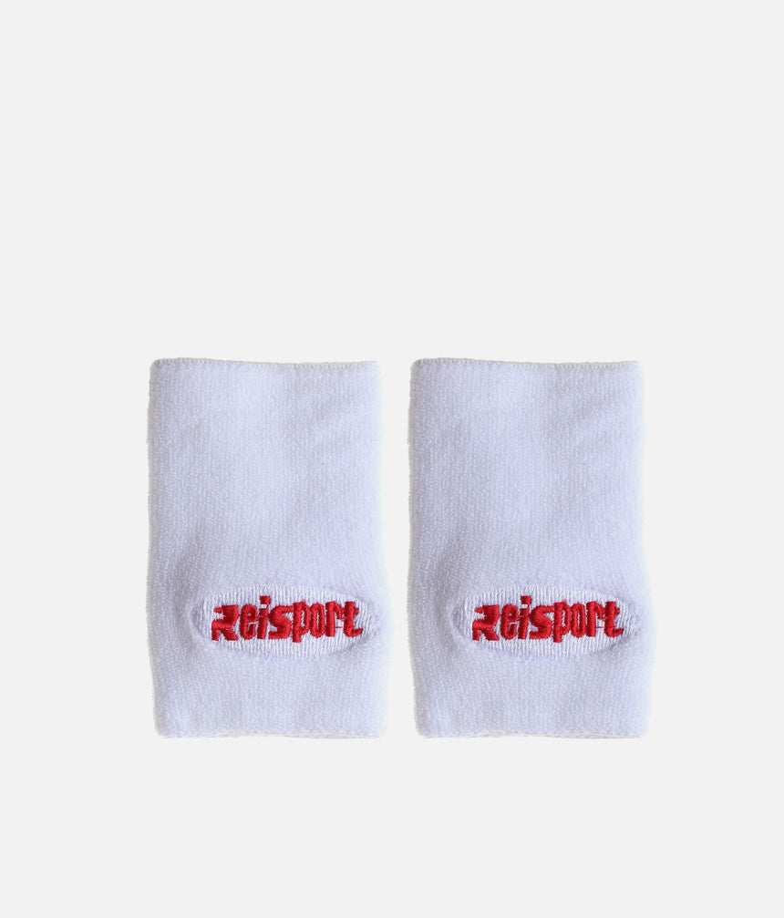 Pair of white Reisport gymnastics wristbands laid flat with red embroidered logos