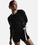 Model wearing Repetto S0797 black side bow sweatshirt with a pale-pink tie, gathered asymmetric hem and black trousers.