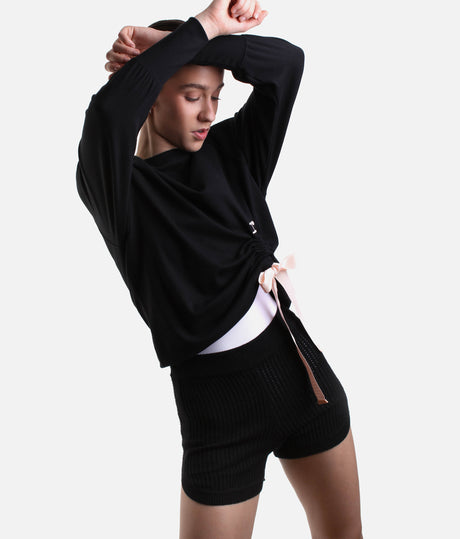 Model wearing Repetto S0797 black side bow sweatshirt with a pale-pink tie, gathered asymmetric hem and black trousers.
