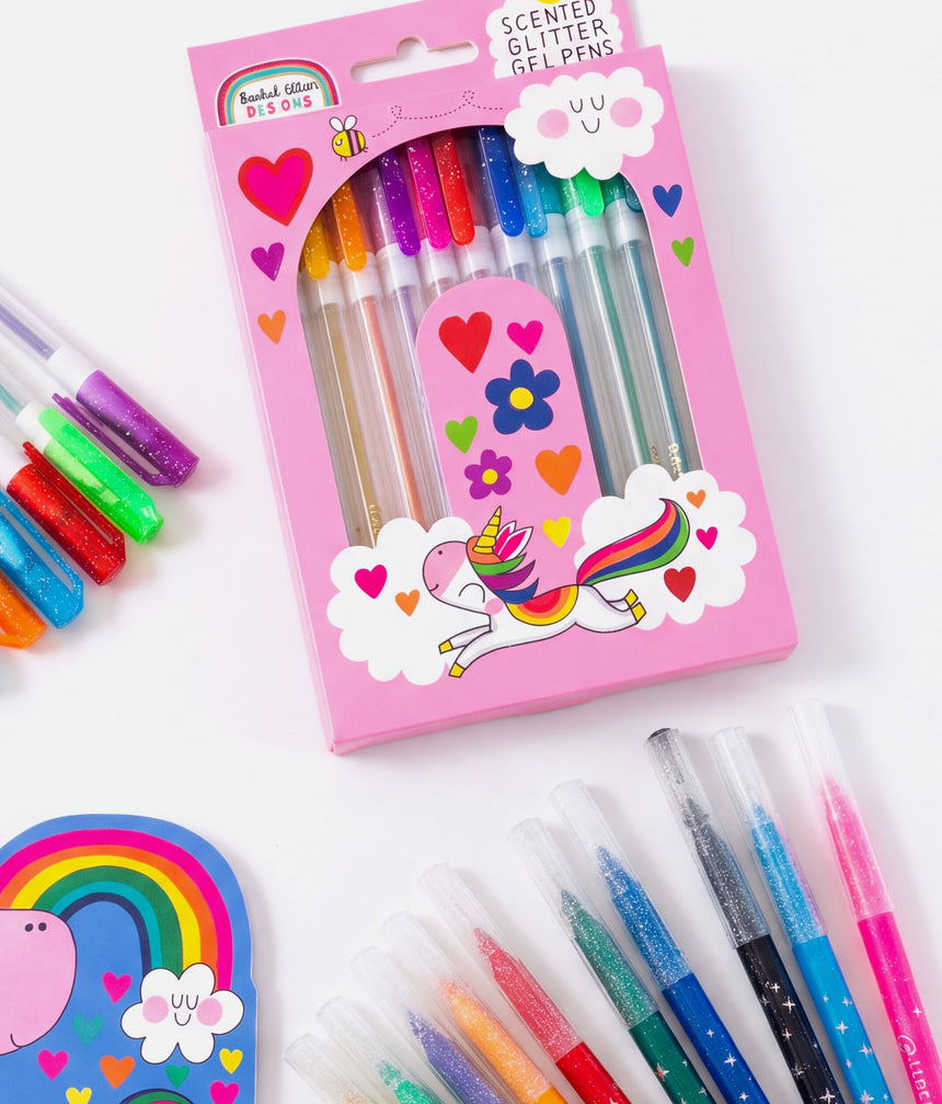 A pink package of scented glitter gel pens with a unicorn illustration, shown on a white background with several loose pens around it.