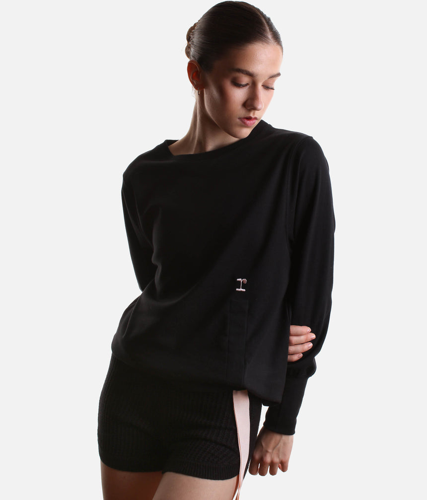 Model wearing Repetto S0797 black side bow sweatshirt with a pale-pink tie, gathered asymmetric hem and black trousers.