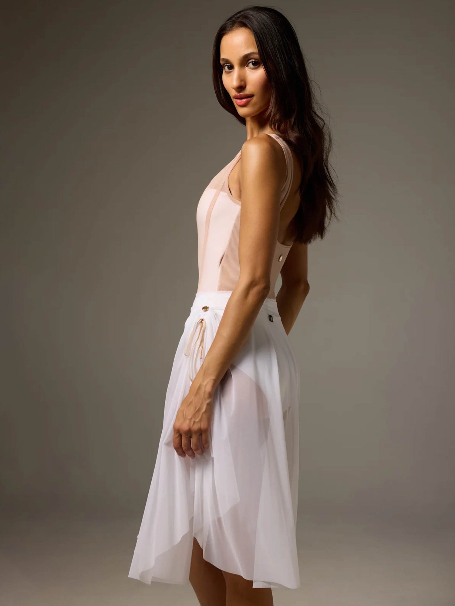 Rear-side view of Bodile Sofia Nougat Frost tank leotard styled with a separate longer white mesh rehearsal skirt.