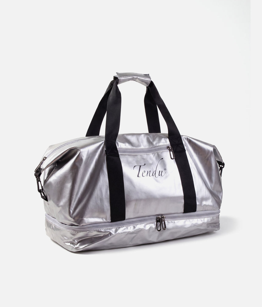 A metallic silver duffel bag with black handles and a black vertical strap, featuring the brand name 'Tendur' printed on the front, set against a plain light gray background.