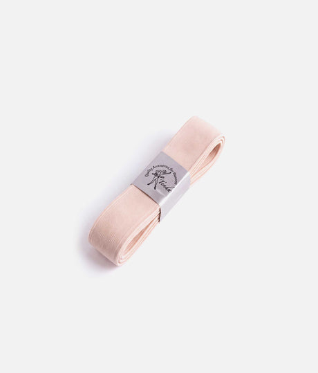 Angled view of folded pale pink Tendu thick pointe shoe elastic with a silver branded band on a white background.